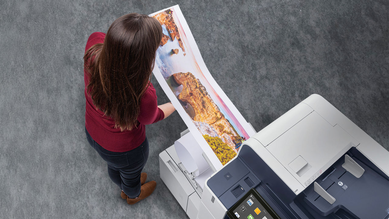 Woman looking at color pages printed on Xerox AltaLink C8100 Series