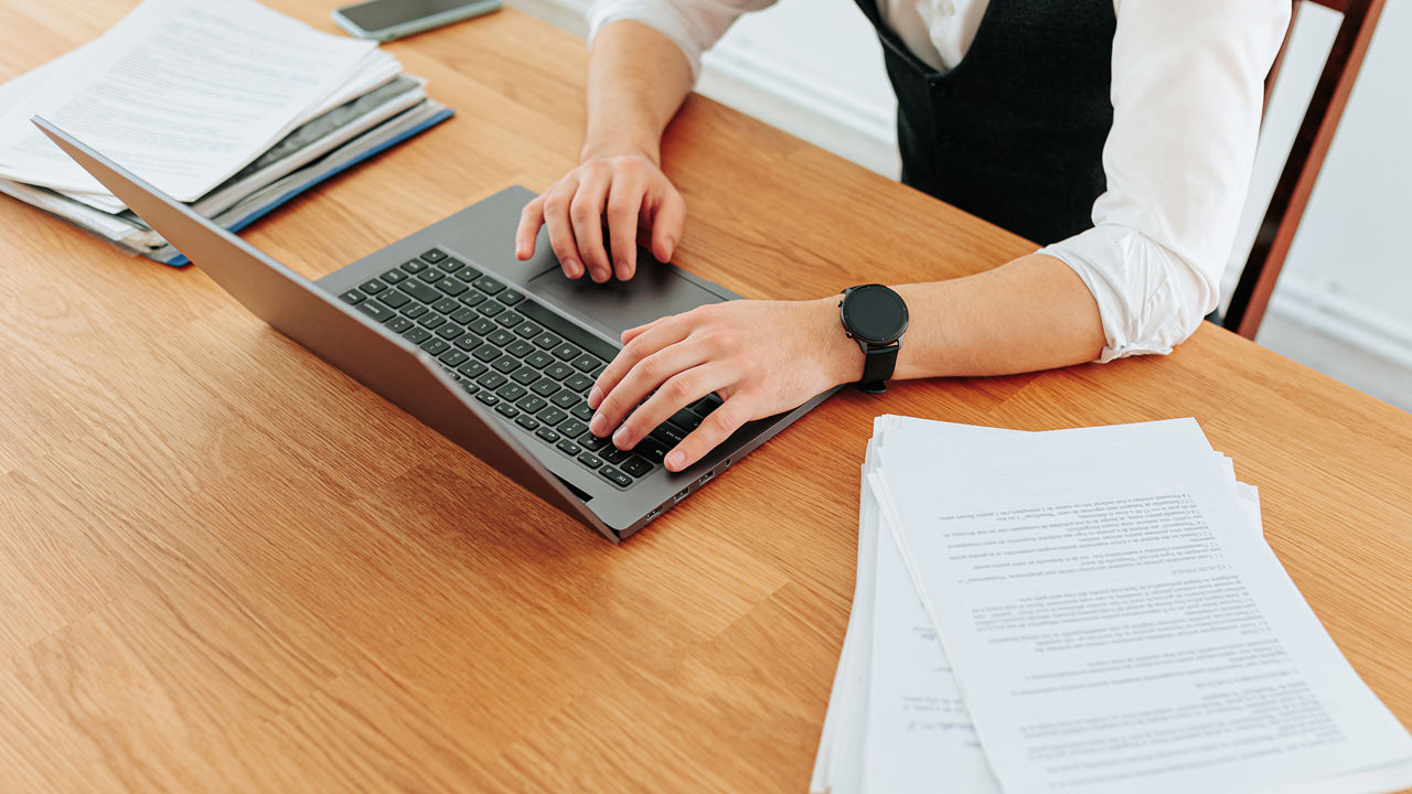 a person using a laptop with paper documents on the table